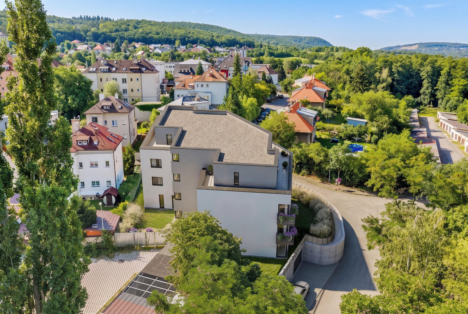 Letecký pohled na Viladům Okružní obklopený zelení z větší vzdálenosti